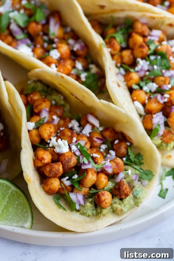 Spiced Chickpea Tacos 5 Freshly assembled chickpea tacos garnished with avocado slices and a squeeze of fresh lime