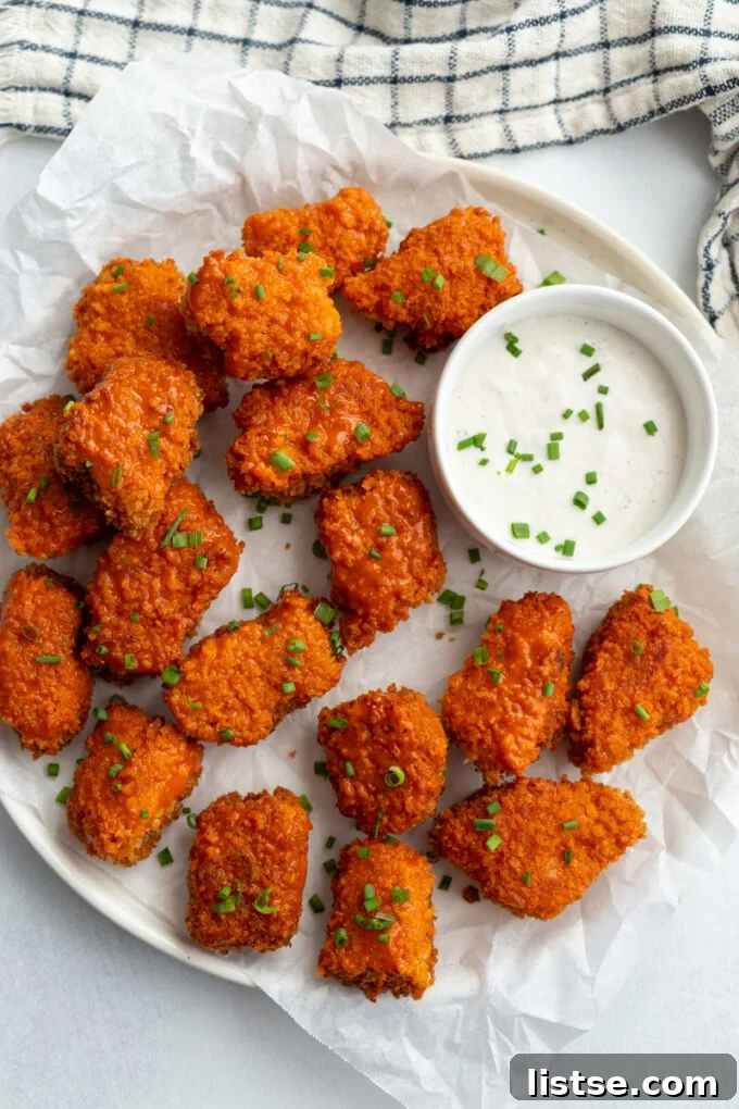 Crispy Buffalo Tempeh Bites 2 Crispy buffalo tempeh wings served on a large white platter with a side of creamy dipping sauce, garnished with fresh herbs.