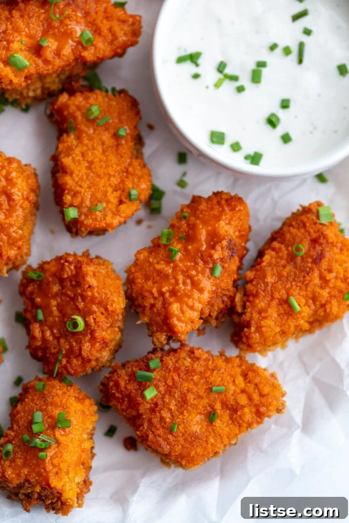 Crispy Buffalo Tempeh Bites 3 Close-up of buffalo tempeh garnished with fresh chives, served with a small bowl of creamy ranch dressing, highlighting its crispy texture.