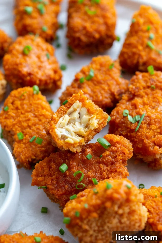 Crispy Buffalo Tempeh Bites 5 Close-up of a buffalo tempeh piece with a bite taken out, revealing the tender interior and crispy breading.