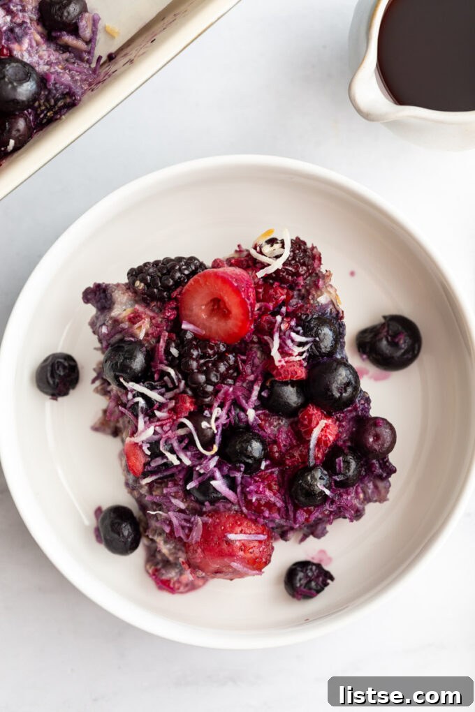 Close-up of berry baked oatmeal served in a small white bowl, showcasing its delicious texture and fruit toppings.