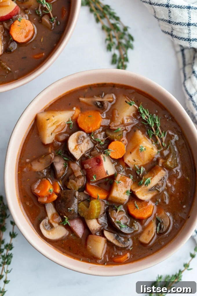 A serving of vegan stew in a small white bowl, garnished with fresh thyme