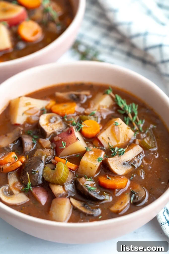 Close-up of vegan stew showing chunks of potatoes, carrots, and mushrooms