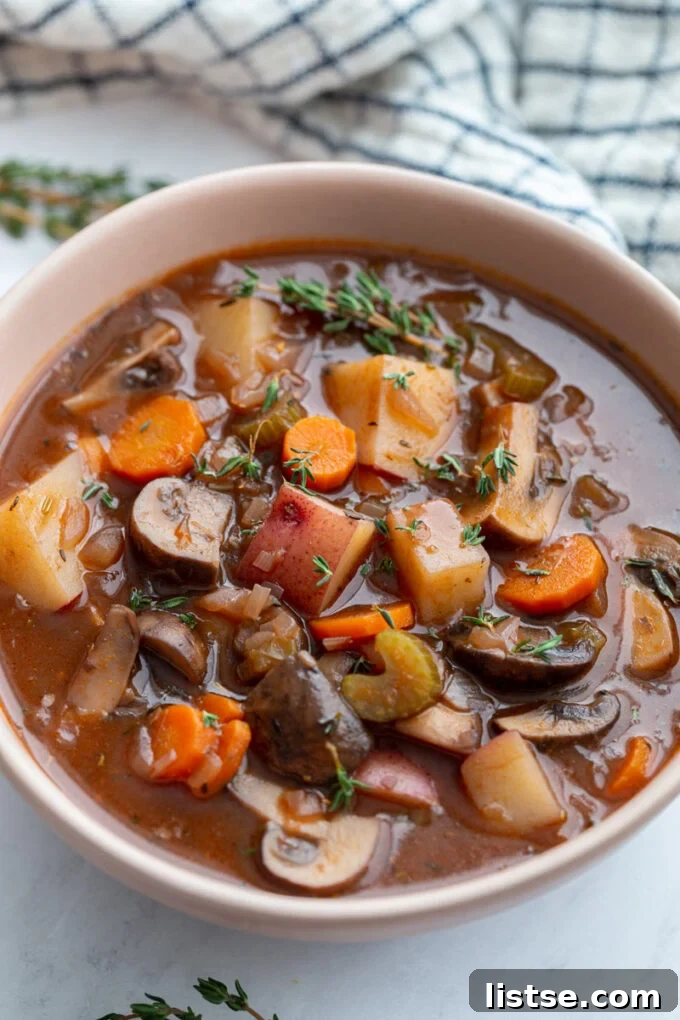 A bowl of meatless stew with vegetables, garnished with fresh thyme leaves