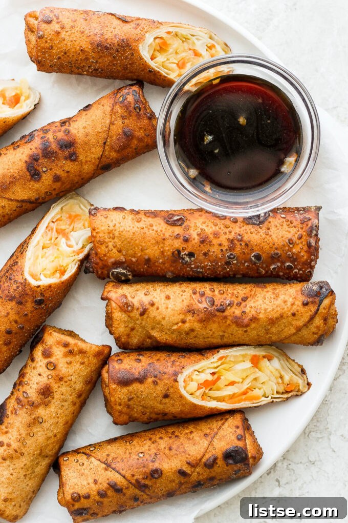 Crispy Vegan Egg Rolls on a white plate with plum sauce, ready to be served.