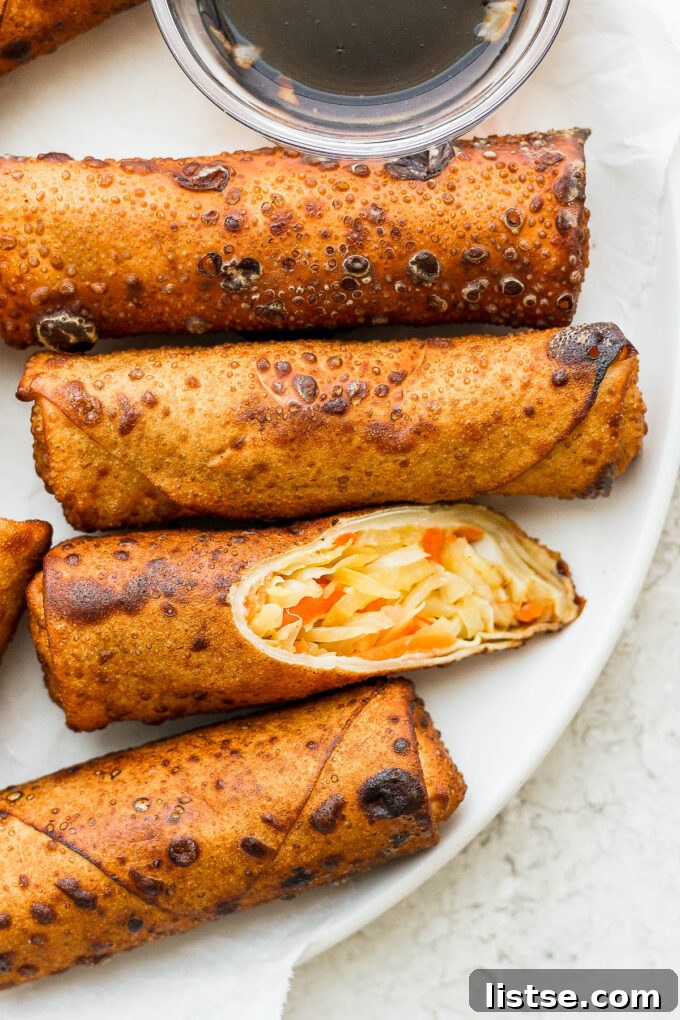A vibrant close-up of vegetarian egg rolls served with a bowl of plum sauce, highlighting their golden crispness.