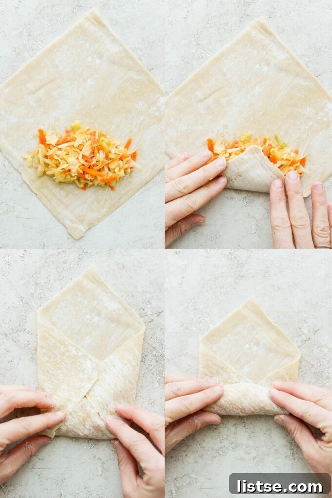 Woman's hand demonstrating the rolling technique for vegan egg rolls on a wooden surface.