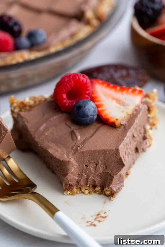 chocolate pie slice with a bite taken out and fresh fruit on top