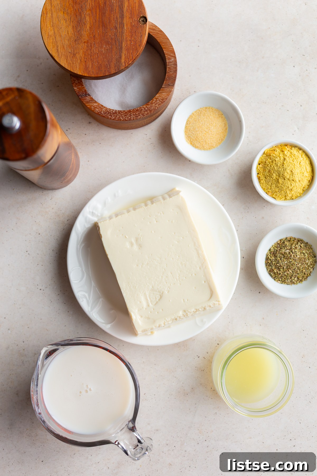Velvety Vegan Alfredo 4 Key ingredients for tofu cream sauce including a block of silken tofu, plant milk, lemon juice, nutritional yeast, and various seasonings.