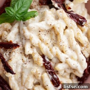 Velvety Vegan Alfredo 9 spiral pasta with creamy white sauce and topped with sun dried tomatoes
