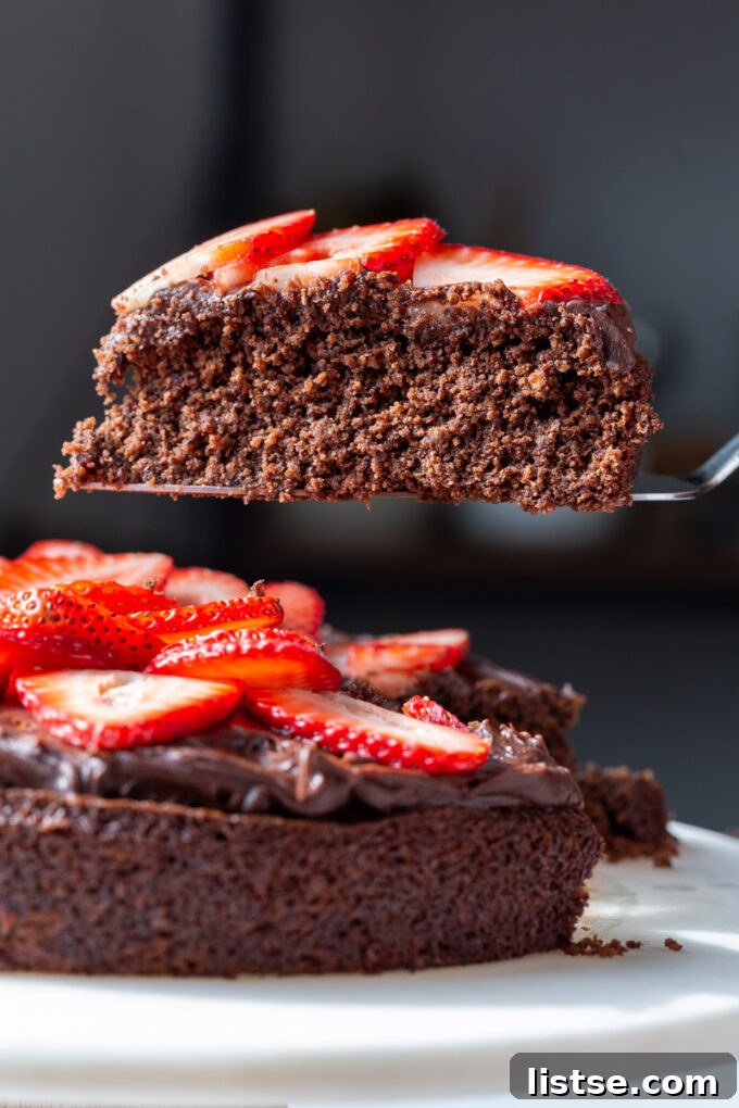 Decadent Vegan Gluten-Free Cake 3 A slice of vegan gluten-free chocolate cake adorned with fresh strawberries, served on a plate.
