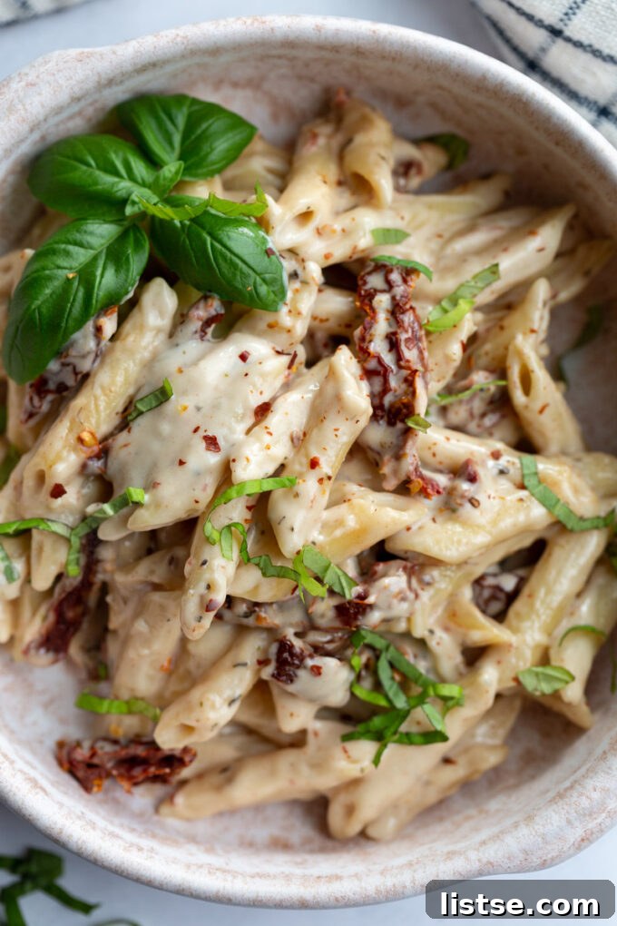 Chickpea pasta topped with fresh herbs and sun dried tomatoes, ready to be enjoyed.