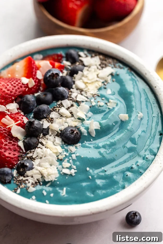Vibrant Blue Spirulina Smoothie 5 A stunning blue smoothie bowl generously topped with fresh berries and delicate shredded coconut.