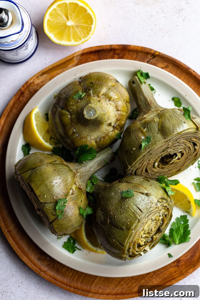 Plated Roman Artichokes, beautifully braised and garnished with fresh herbs and lemon