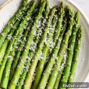 Cooked asparagus on a plate with a sprinkle of parmesan cheese.