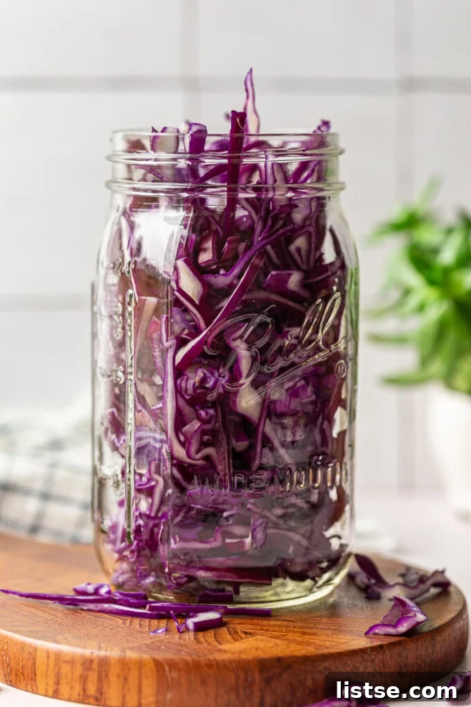 Stuffing red cabbage into a large mason jar.