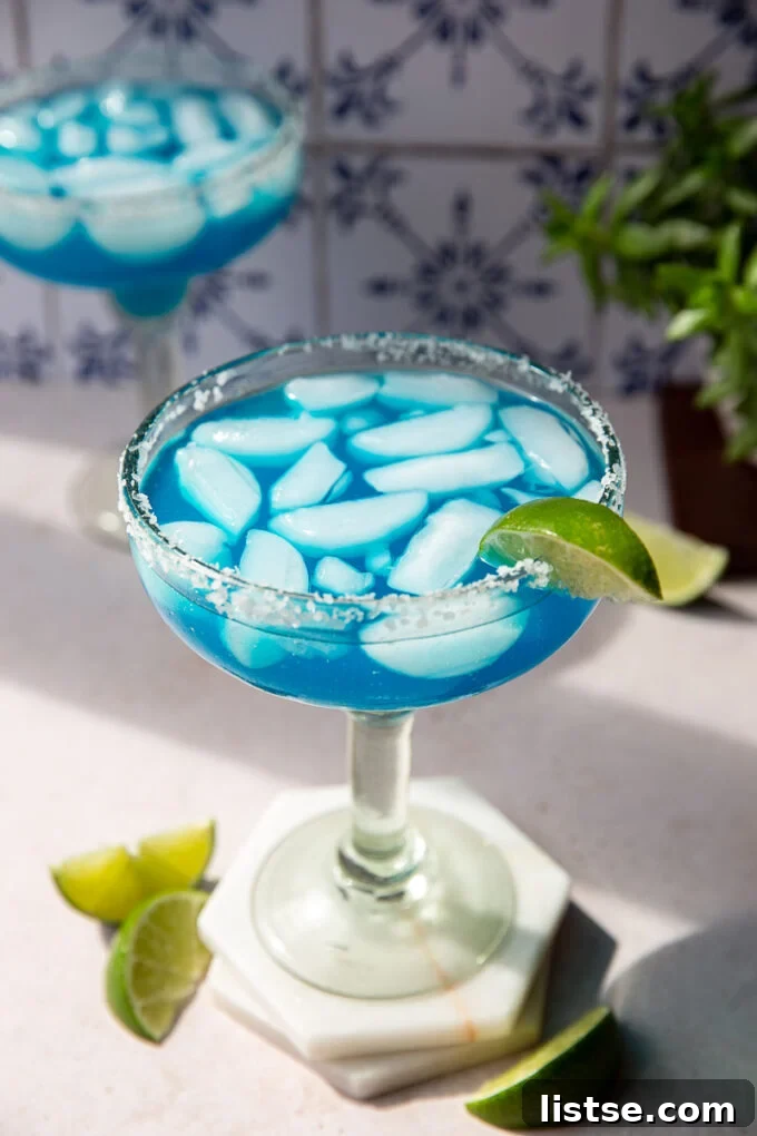 Ocean Breeze Margarita 5 A vibrant blue cocktail with a perfectly salted rim, garnished with lime wedges, ready for enjoyment.