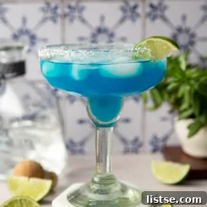 Blue margarita served with lime slices.