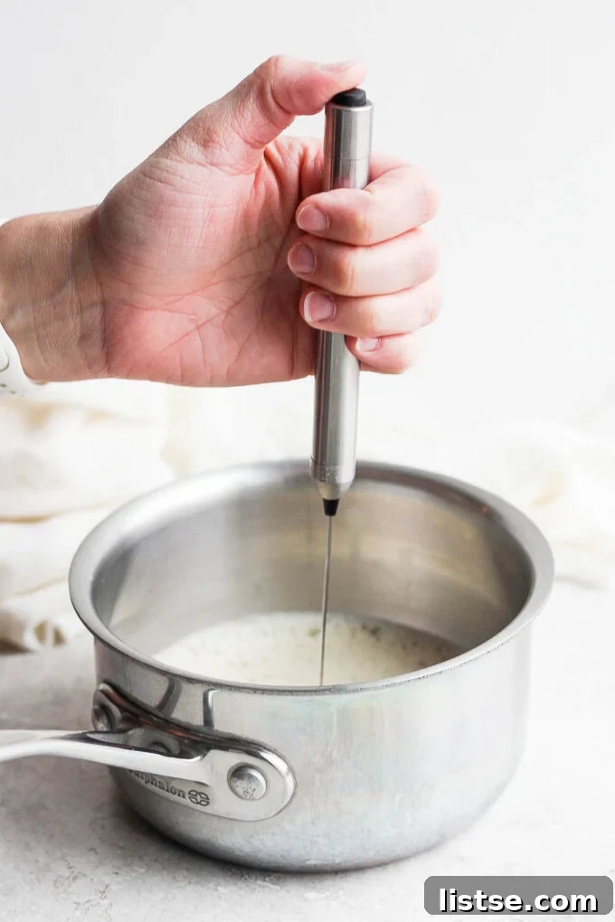 Velvet Caramel Dream 5 A hand using a frother to create foam in a pot of milk.