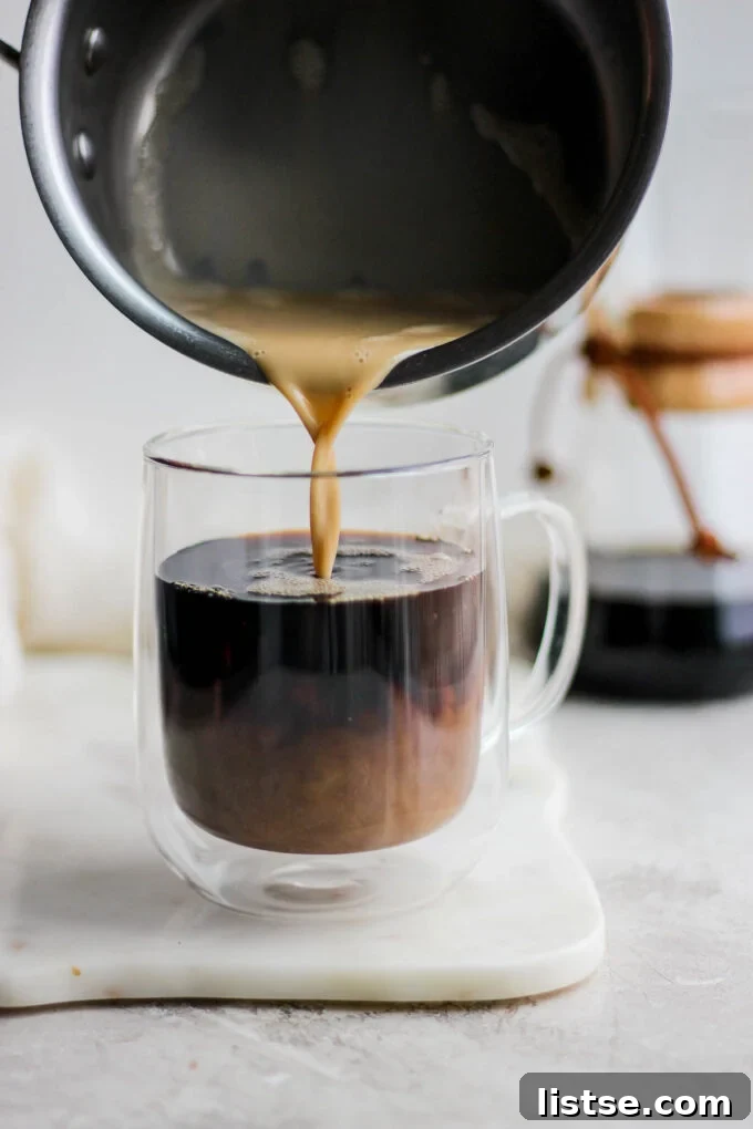 Velvet Caramel Dream 6 Pouring frothed milk into a mug of hot coffee to create a latte.