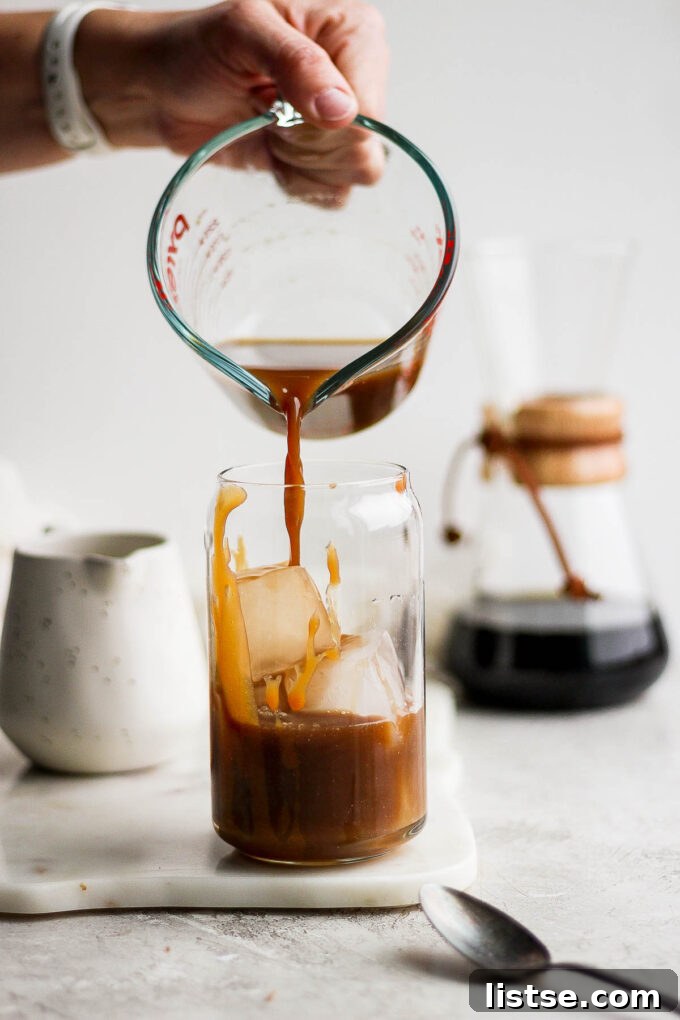 Pouring coffee mixture into a glass with ice.