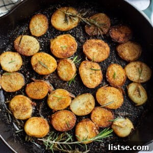 Rosemary pan-fried potato coins in a skillet, ready to serve.
