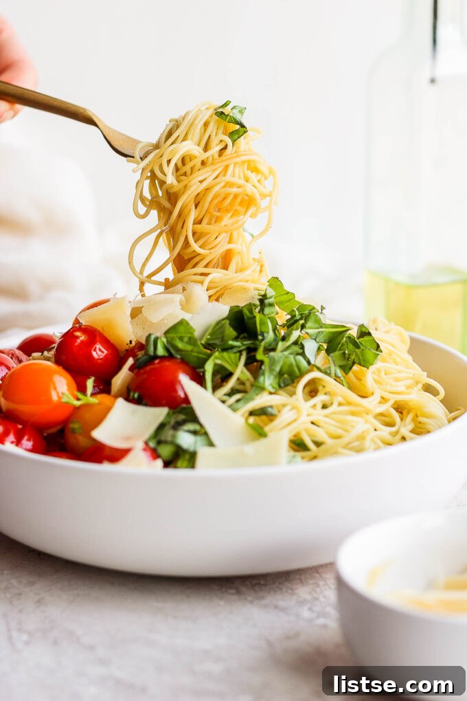 A fork twirling a generous portion of angel hair pasta, showing its delicate strands coated in sauce.