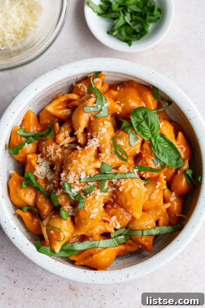 Creamy pasta shells with spicy vodka sauce, garnished with fresh basil leaves, ready to be served.