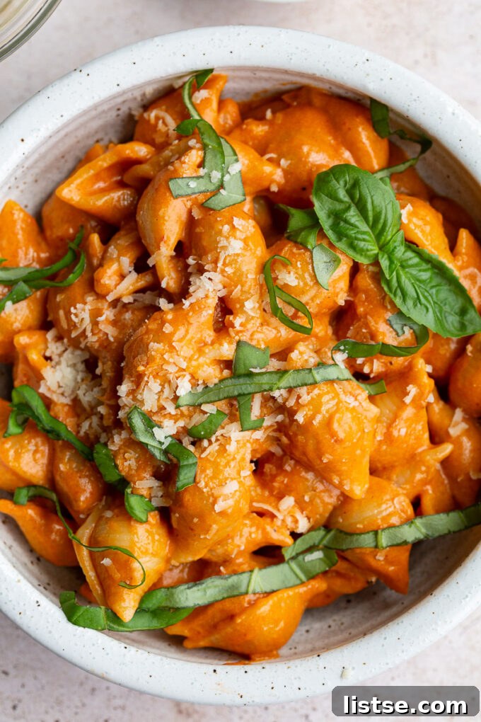 A small white bowl filled with creamy Gigi Hadid pasta, garnished with fresh basil leaves.