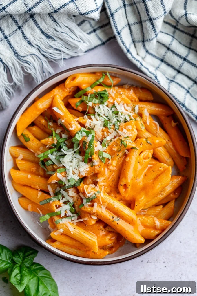 Roasted red pepper pasta served in a small bowl, garnished with fresh basil.