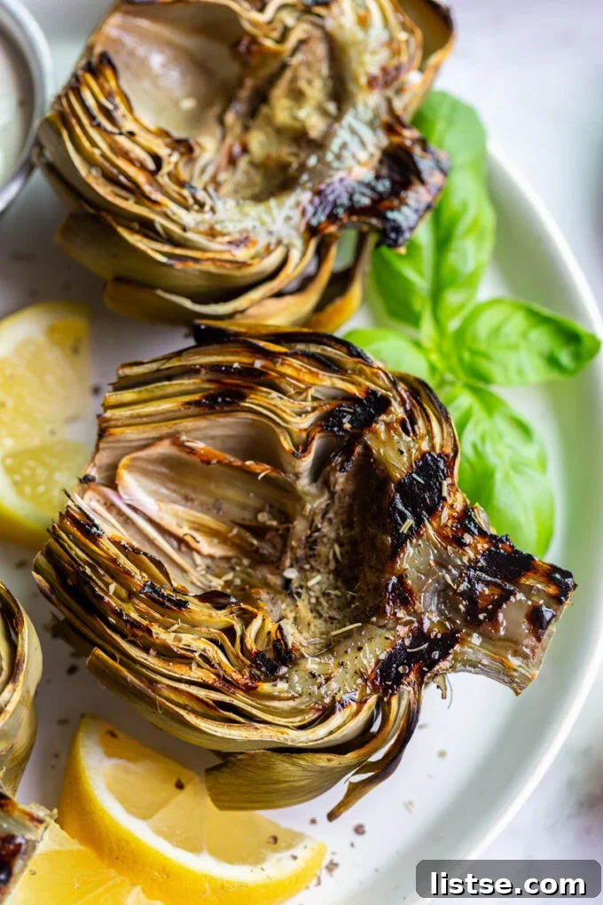 Sizzling Vegetarian Grills 13 Perfectly grilled artichokes presented on a plate, garnished with fresh lemon wedges, ready to be enjoyed as a savory side.