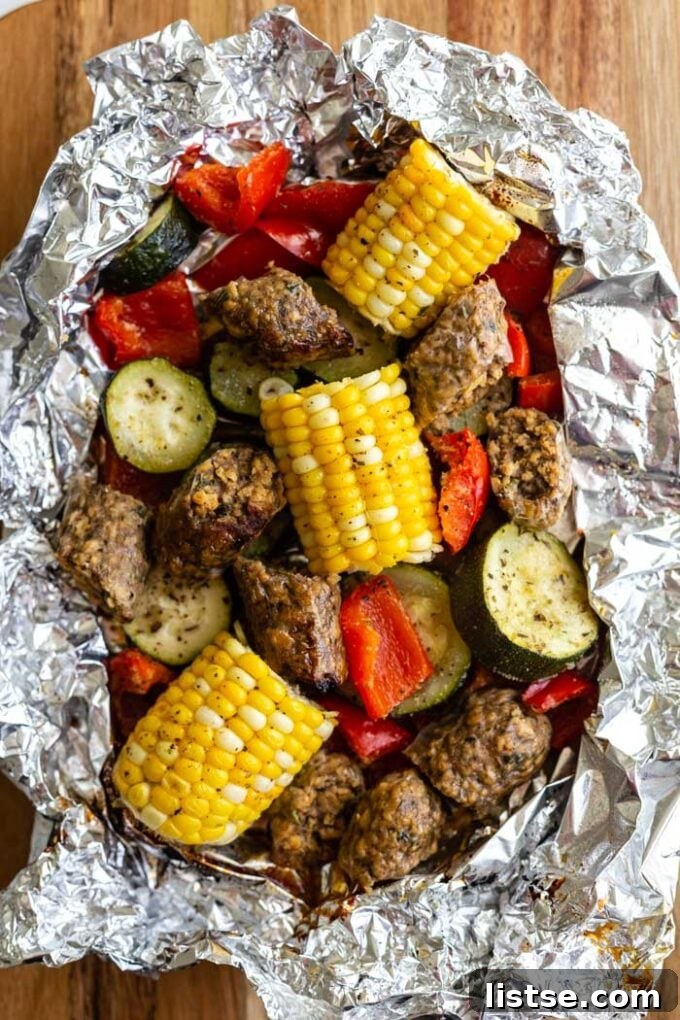 Sizzling Vegetarian Grills 4 A perfectly cooked foil pack meal, revealing grilled vegan sausage, corn on the cob, and zucchini, bursting with summer flavors.