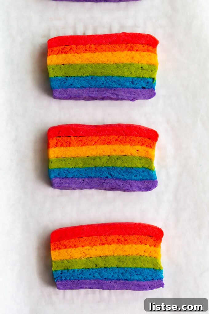 Close-up shot of multiple Vegan Pride Flag Sugar Cookies, each displaying perfect rainbow stripes, on a clean white surface.