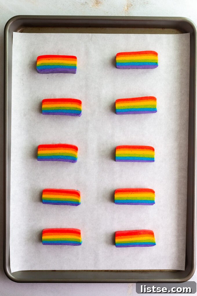 Six separate mounds of vibrantly colored vegan cookie dough, ready for shaping, on a white background.