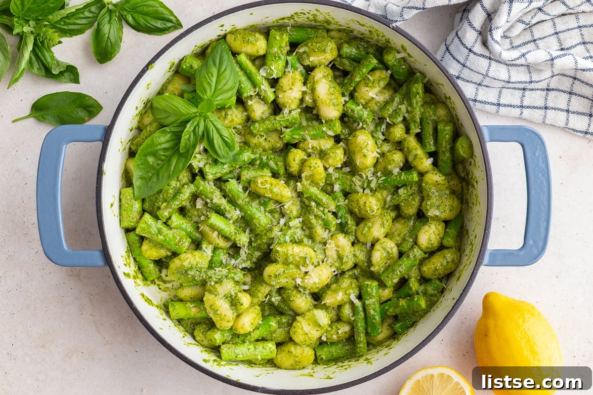 Pesto gnocchi in a large skillet, garnished with fresh basil and lemon slices, ready to be served.