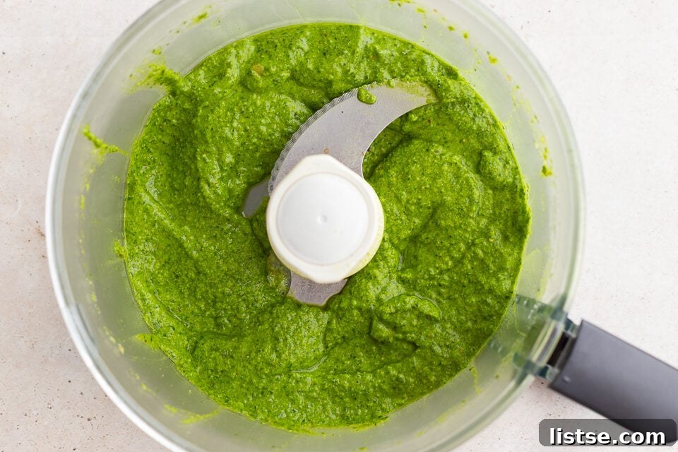 Fresh homemade pesto being blended to a smooth consistency in a food processor.