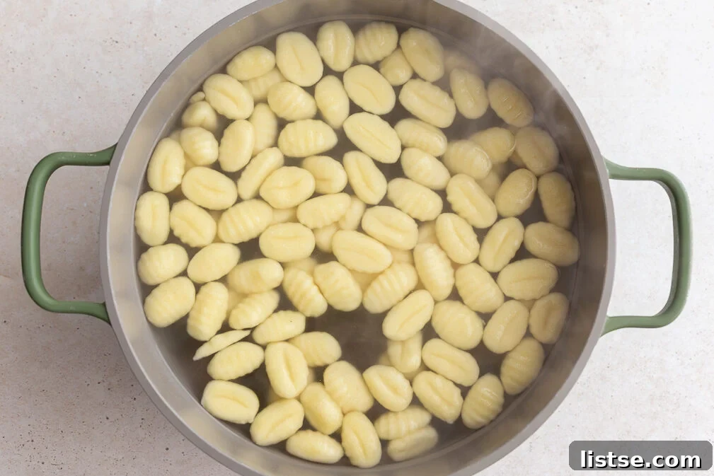 Gnocchi gently simmering in a large pot of boiling water on a stovetop.