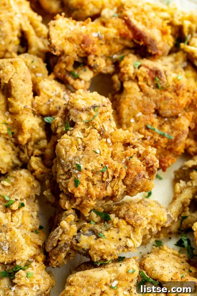 Crispy Oyster Mushrooms 3 Close-up of golden-brown fried mushrooms garnished with fresh parsley.