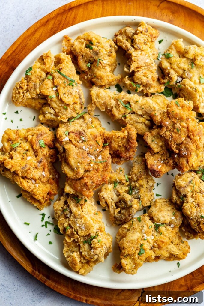 Crispy Oyster Mushrooms 4 A serving of golden-brown fried oyster mushrooms on a white plate, ready to be enjoyed.