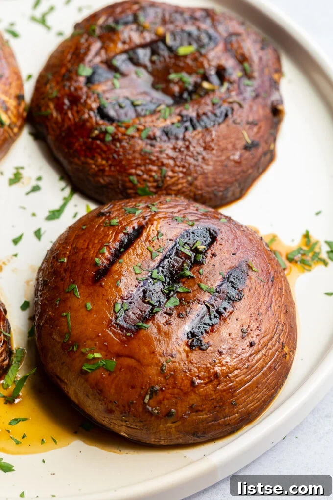 Perfectly grilled Portobello mushrooms, seasoned with fresh herbs, presented on a pristine white plate.