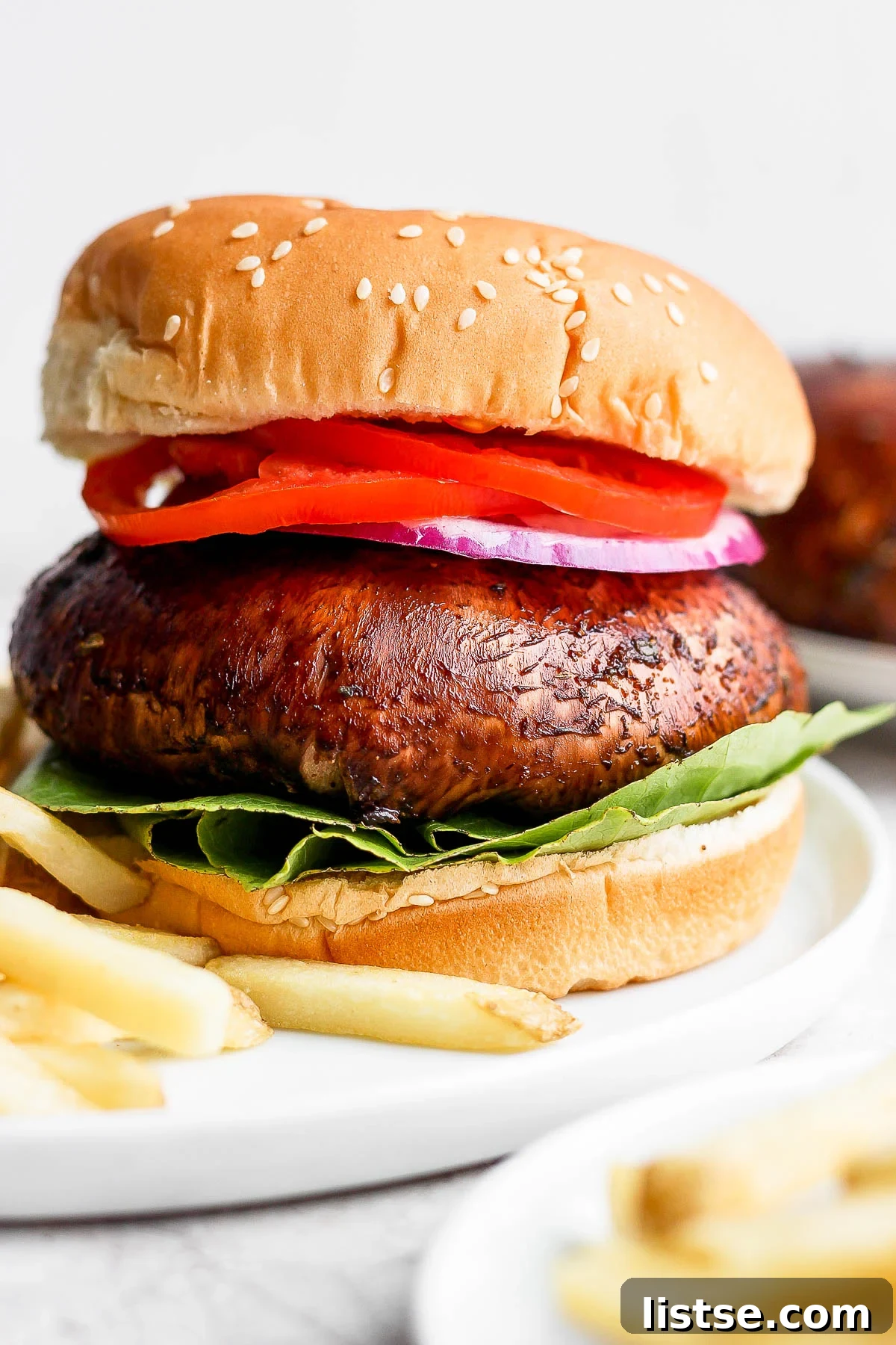Gourmet Portobello Burgers 2 Juicy Portobello mushroom burger served alongside a pile of golden French fries, ready to be enjoyed.