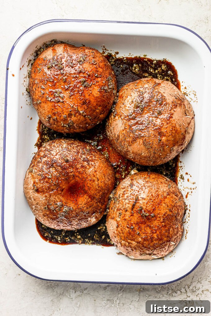 Gourmet Portobello Burgers 4 Fresh Portobello mushrooms soaking in a rich, dark marinade in a shallow dish, absorbing all the delicious flavors.