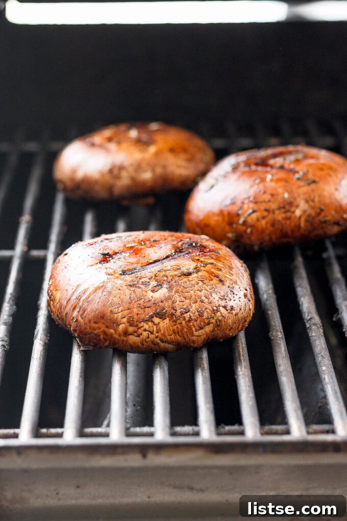 Gourmet Portobello Burgers 5 Two large Portobello mushrooms sizzling on a hot grill, showing char marks and a glossy marinade.
