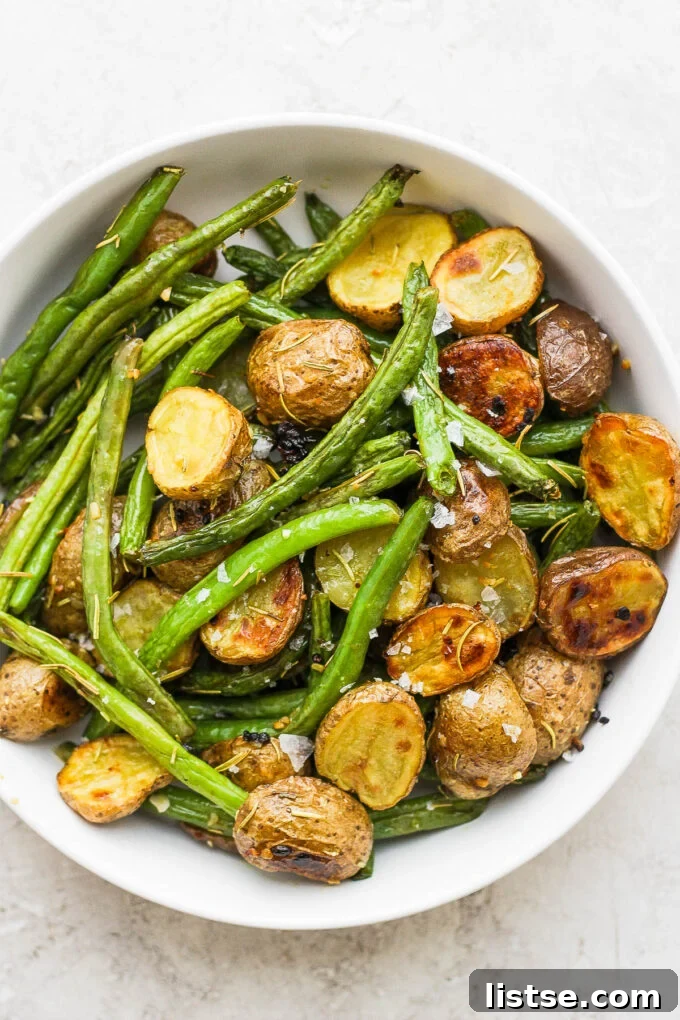 Golden Roasted Potatoes with Tender-Crisp Green Beans 2 Roasted Potatoes and Green Beans in a white serving bowl, garnished with fresh herbs.