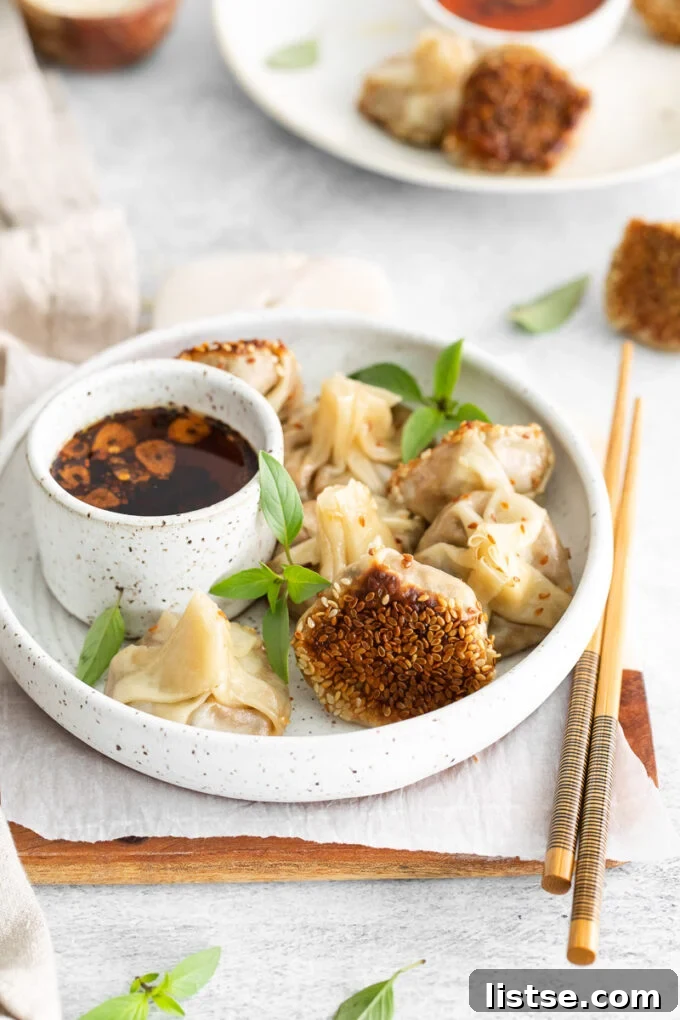 Plant-Powered Parcels 7 Three perfectly pan-fried vegan dumplings, garnished with green onions and sesame seeds, are artfully arranged with chopsticks on a white plate.