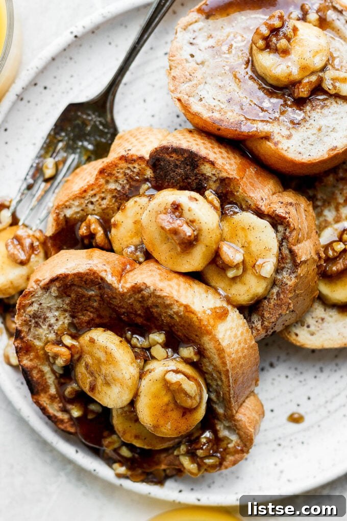 Bananas Foster French Toast served on a white plate, garnished with powdered sugar and a mint sprig.