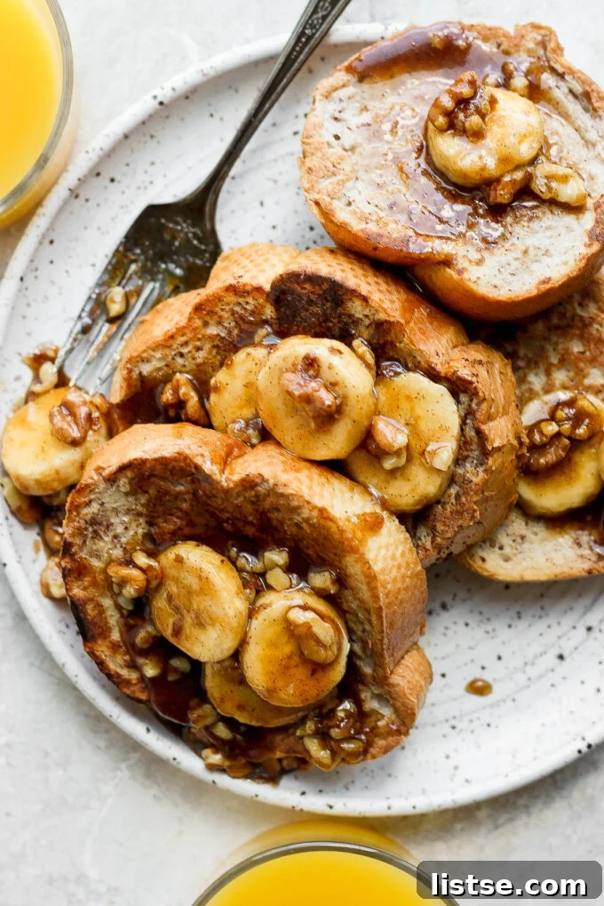 A stack of Bananas Foster French Toast garnished with a sprig of mint and powdered sugar.