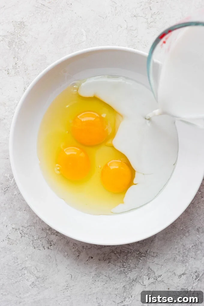 Pouring milk in a bowl with three eggs.