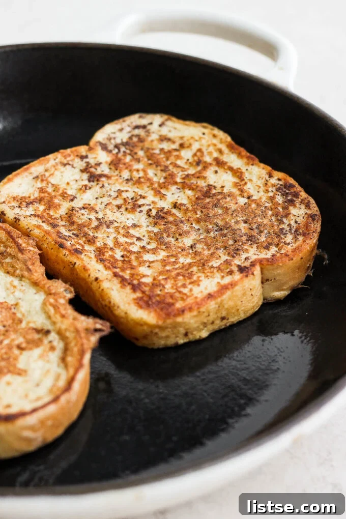 Slice of French toast cooking in a pan.