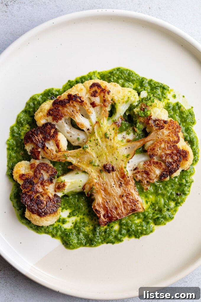 Savory Cauliflower Cutlets 2 Perfectly golden-brown roasted cauliflower steak served on a white plate, generously drizzled with fresh, vibrant green chimichurri sauce, highlighting its tender interior and crispy, charred edges.